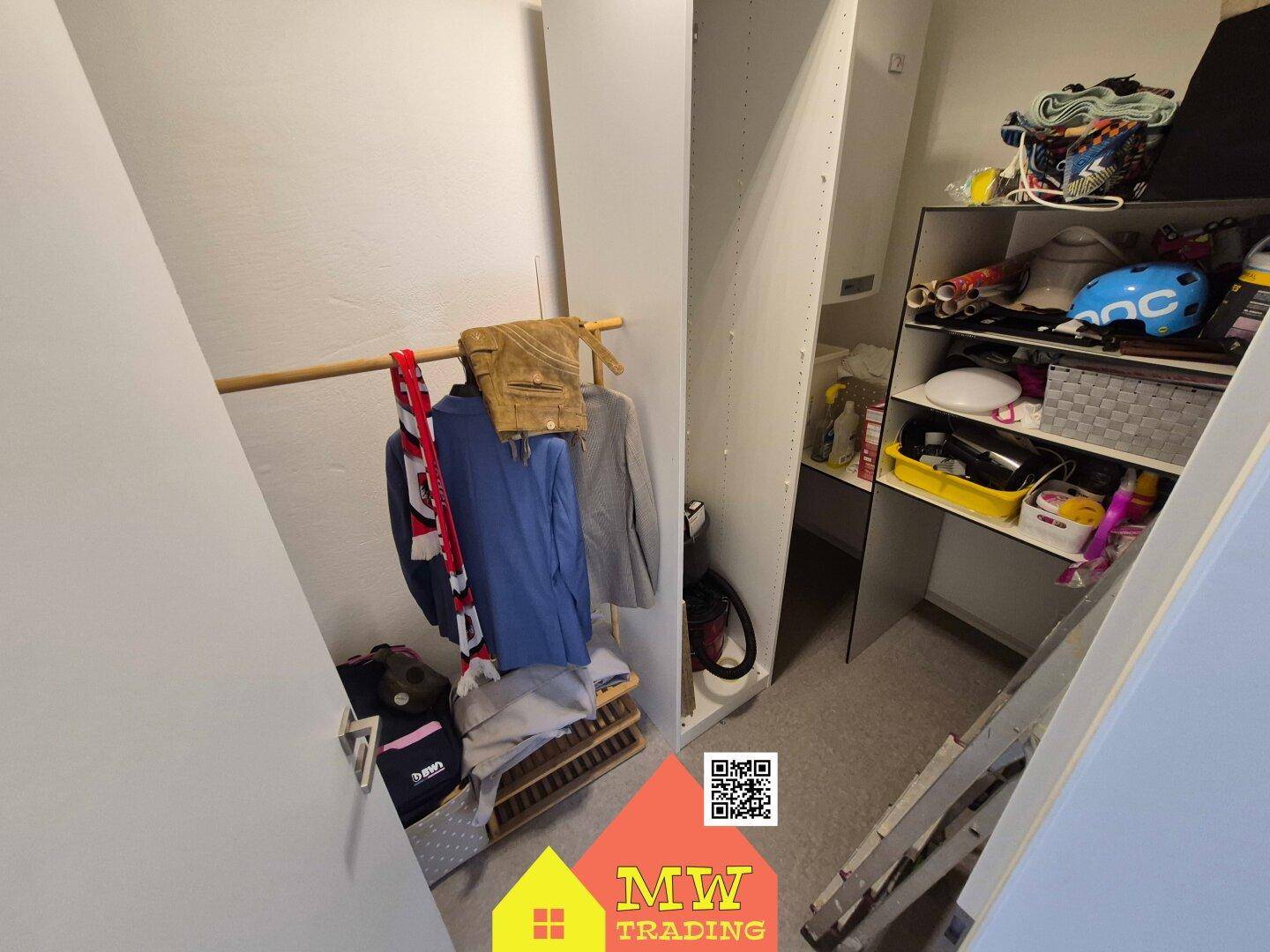 Praktischer Abstellraum mit Regalen und Kleiderstange unter einer Dachschräge.