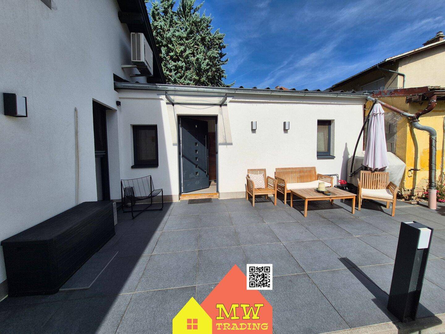 Detailansicht der Terrasse mit Sitzgelegenheiten und dem Hintereingang des Hauses.