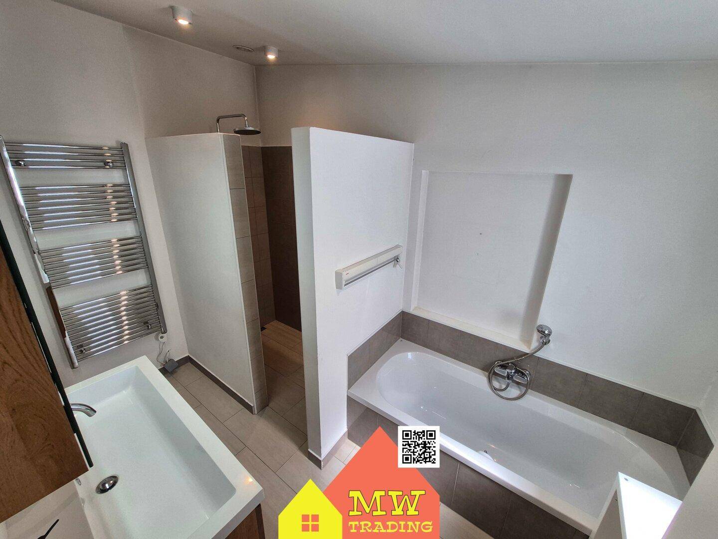 Modernes Badezimmer mit Badewanne, Dusche und beheiztem Handtuchhalter.