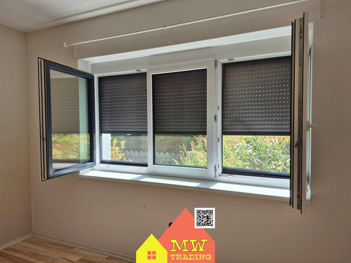 Fenster mit geöffneten Rollläden und Blick ins Grüne, das Zimmer ist hell.