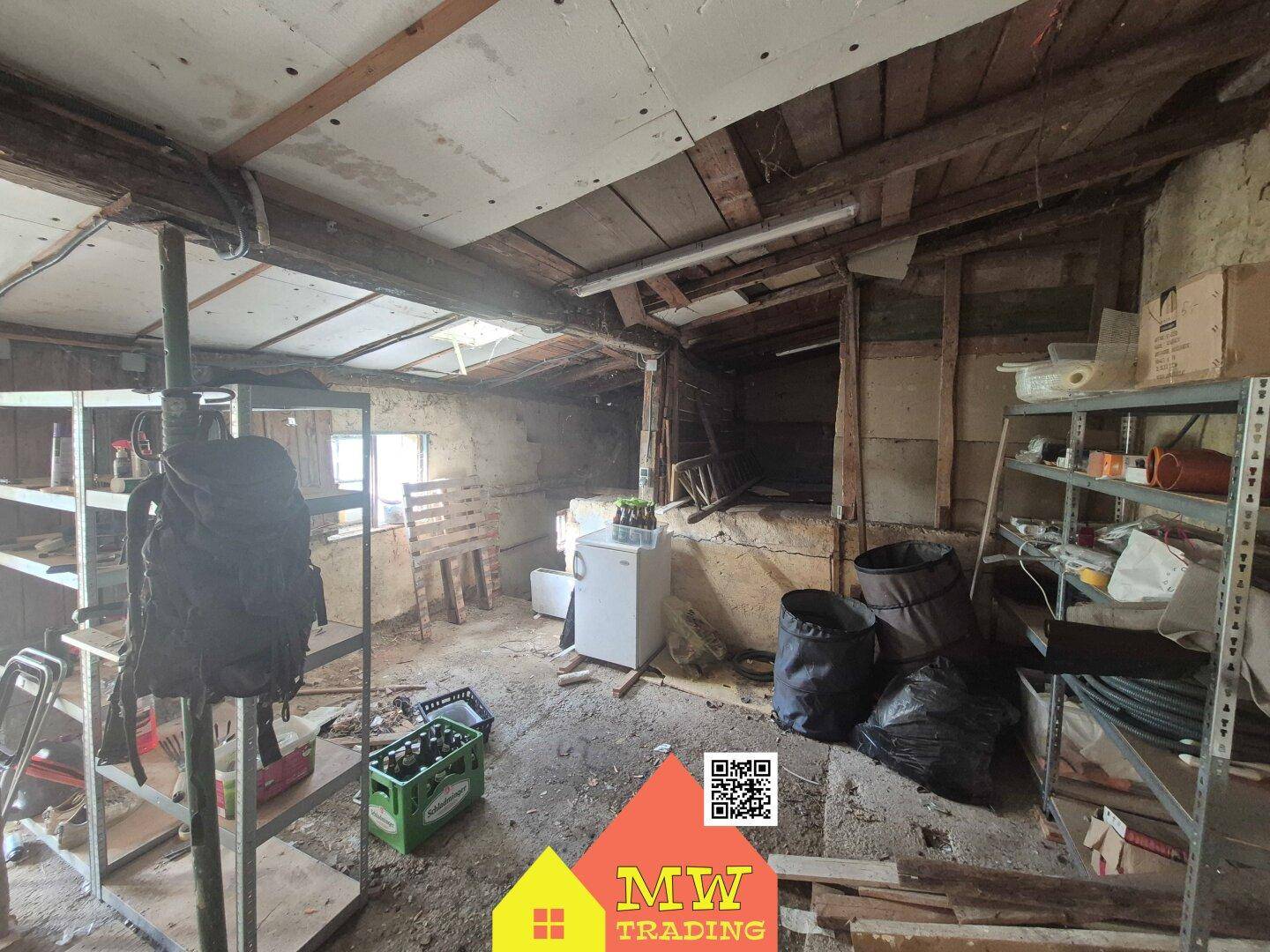Geräumiger Abstellraum mit vielen Gegenständen, sichtbaren Deckenbalken und unfertigen Wänden.
