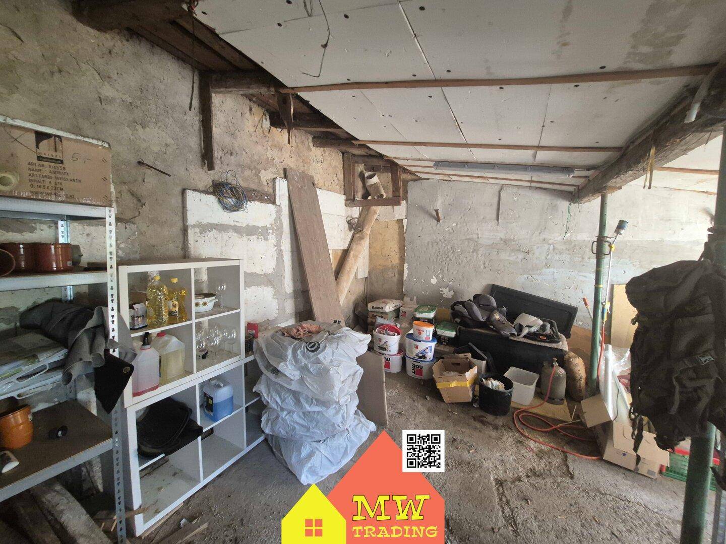 Unaufgeräumter Lagerraum mit Regalen, verschiedenen Gegenständen und sichtbarer Deckenkonstruktion.