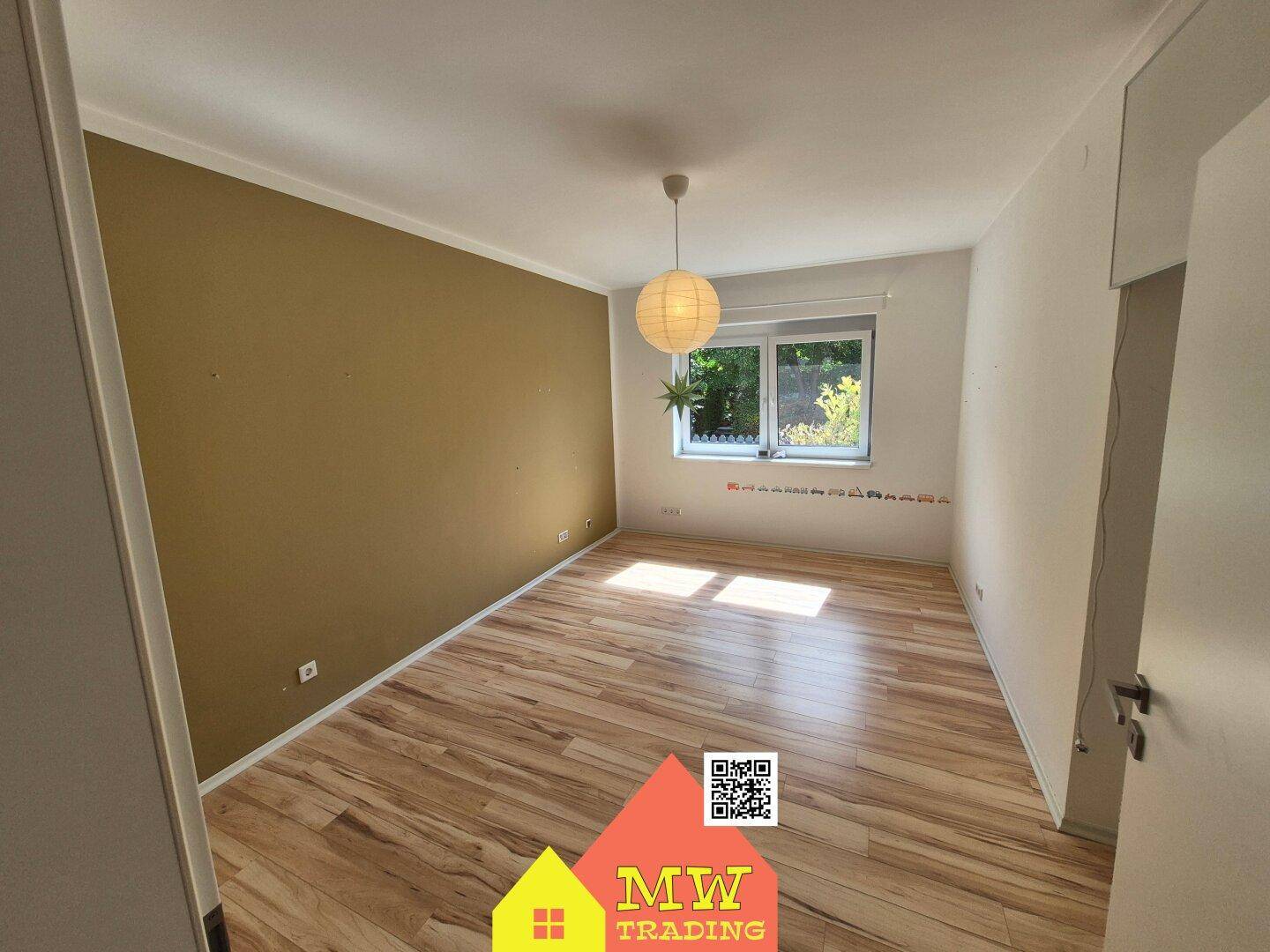 Helles Schlafzimmer mit Holzboden und einer farbigen Akzentwand.