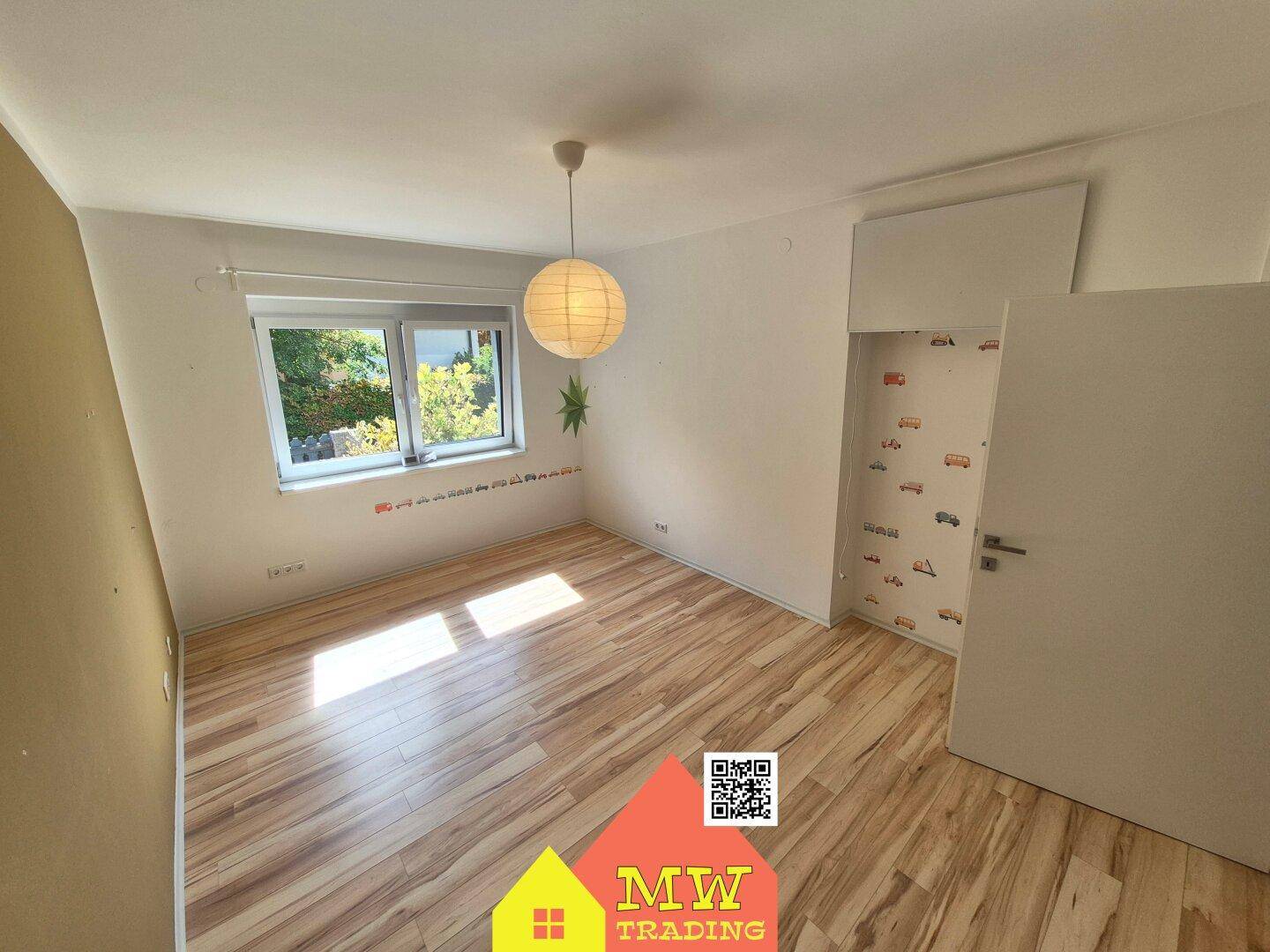 Schlafzimmer mit Holzboden, Fenster und verspielter Tapete im Schrankbereich.