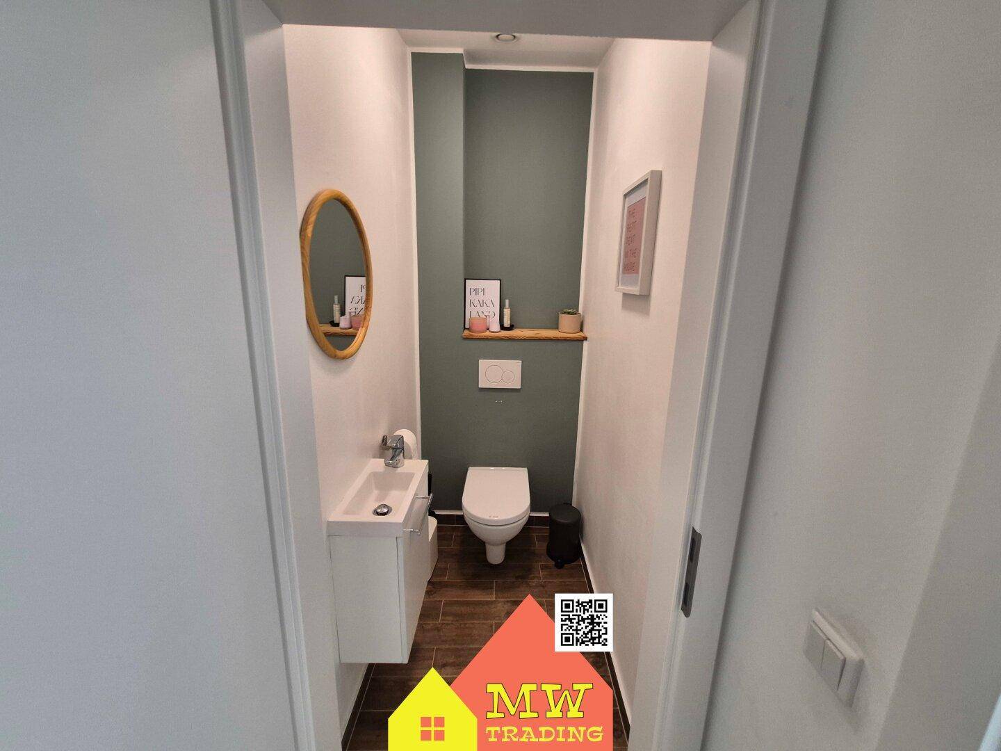 Modernes Gäste-WC mit Wand-WC, kleinem Waschbecken und grünem Akzent.
