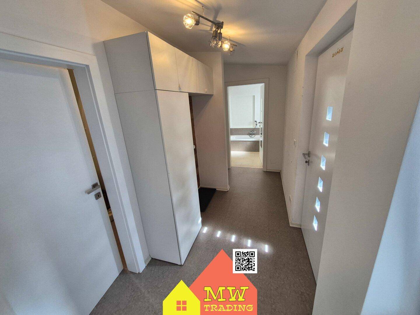 Heller Flur mit modernen Einbauschränken und Blick in ein weiteres Zimmer.