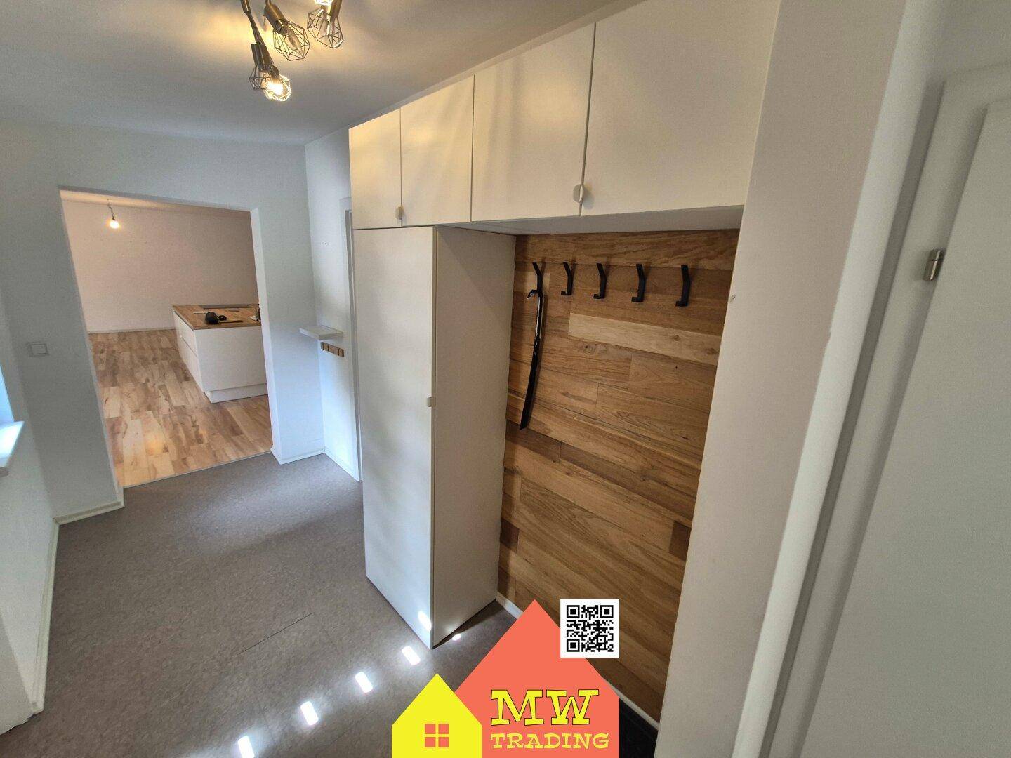 Eingangsbereich mit Garderobe und Holzverkleidung, führt zu einem offenen Wohnbereich.