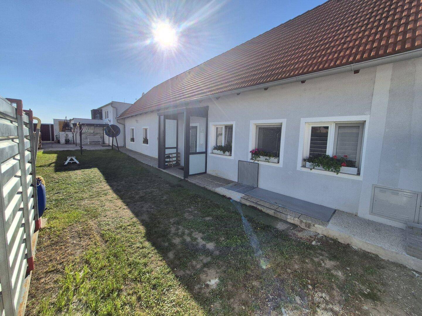 Seitenansicht des Hauses mit gepflegtem Rasen und einem Weg unter strahlendem Sonnenschein.