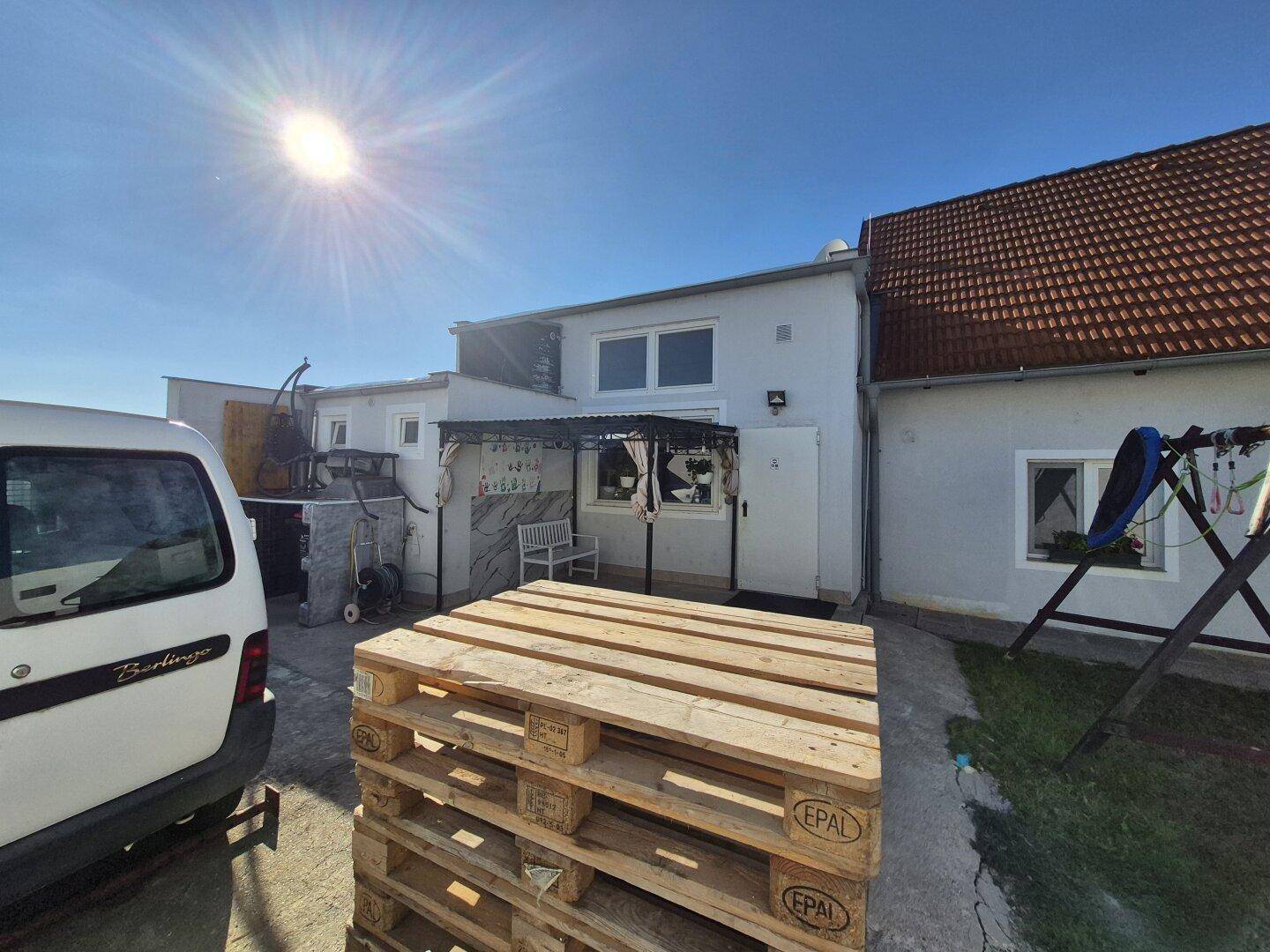 Hinterhofbereich des Hauses mit einer überdachten Terrasse und einem geparkten Lieferwagen.