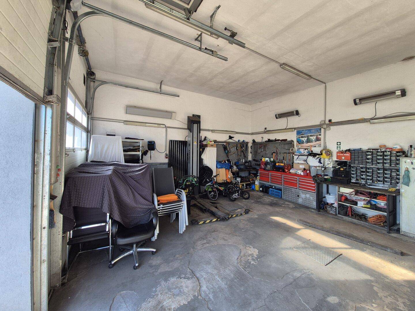 Geräumige Werkstatt mit Hebebühne, Werkbänken und vielen Werkzeugen, bereit für Reparaturen.