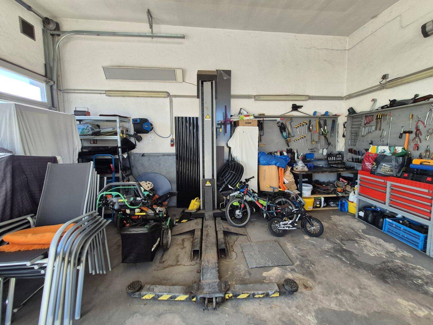 Detailansicht der Hebebühne in der Werkstatt, umgeben von Werkzeugen und Ersatzteilen.