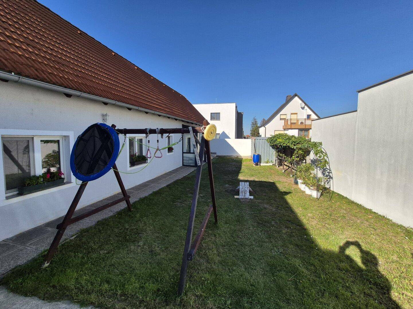 Gepflegter Gartenbereich mit Rasen, Schaukel und Blick auf die umliegenden Wohngebäude.