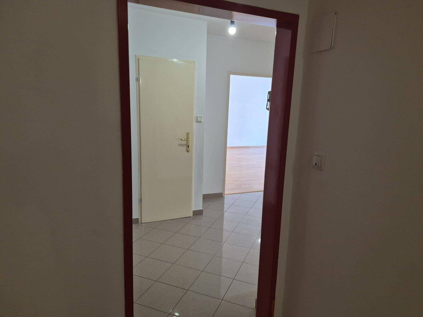 Gefliester Flur mit mehreren Türen, der den Zugang zu verschiedenen Räumen der Wohnung ermöglicht.