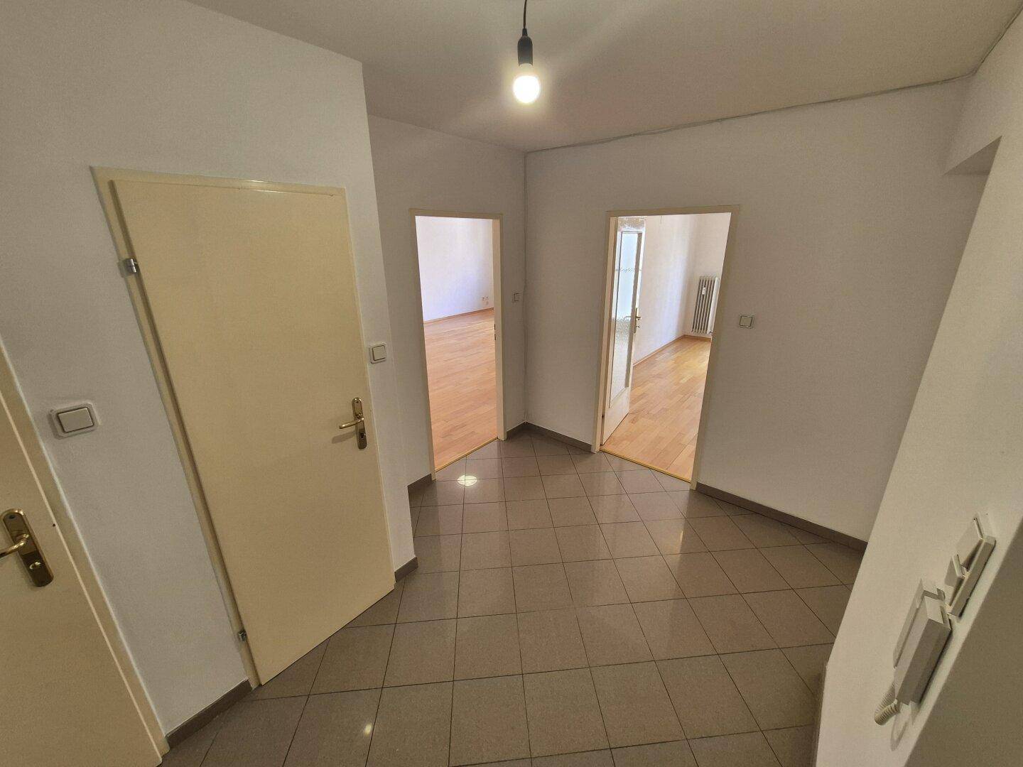 Heller Flur mit Fliesenboden und mehreren Türen, die zu den angrenzenden Zimmern führen.