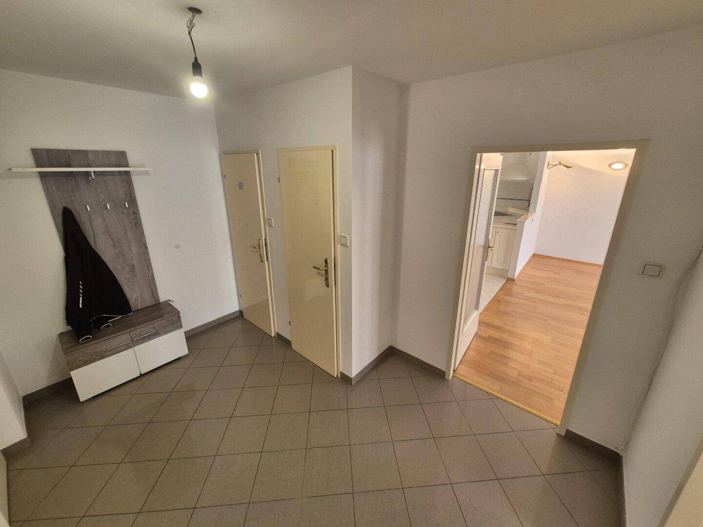 Eingangsbereich mit Fliesenboden und einer Garderobe, die zu weiteren Räumen führt.
