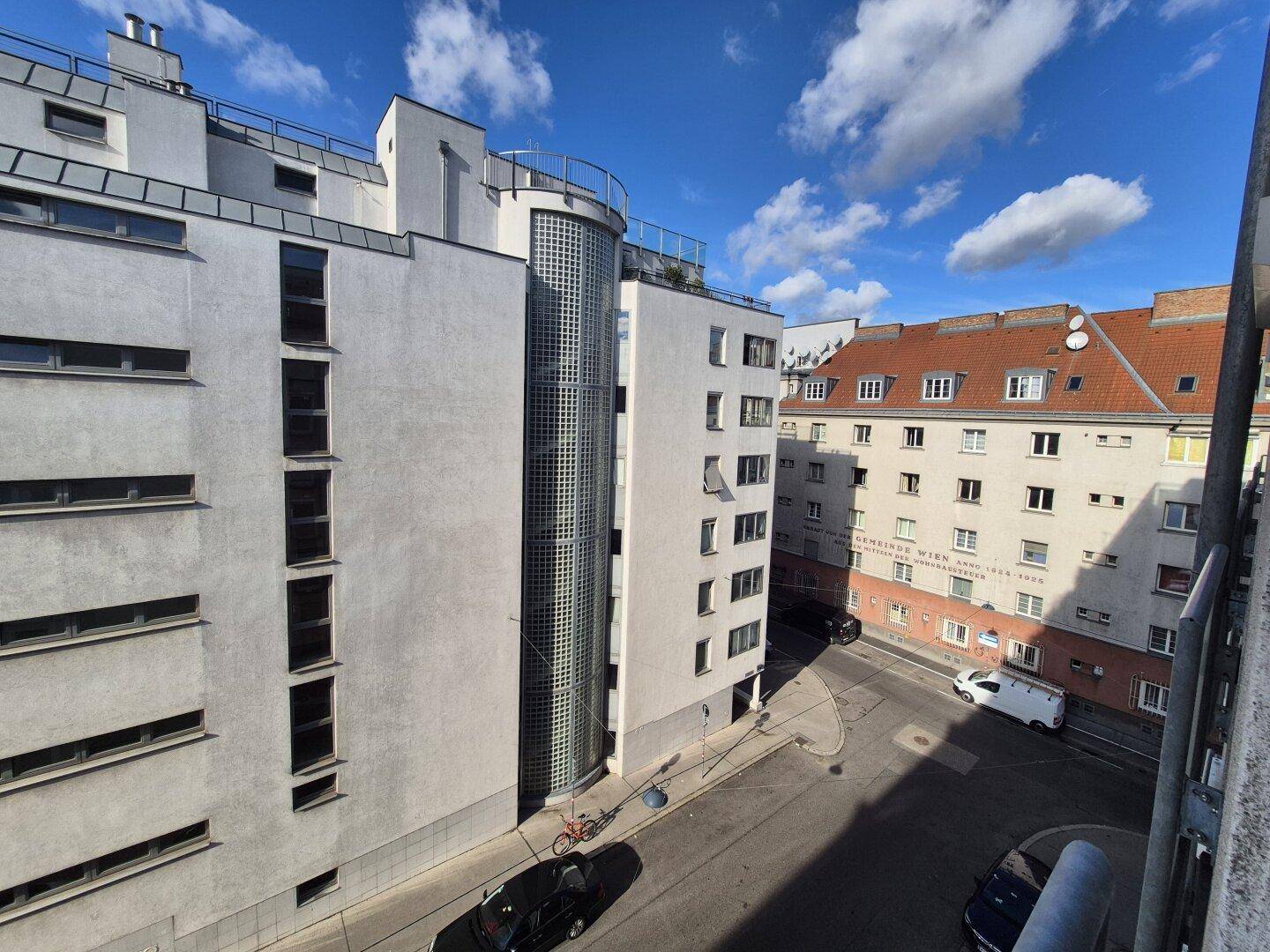 Blick auf die moderne Architektur eines Wohngebäudes mit Glasfassade und umliegenden Straßen.