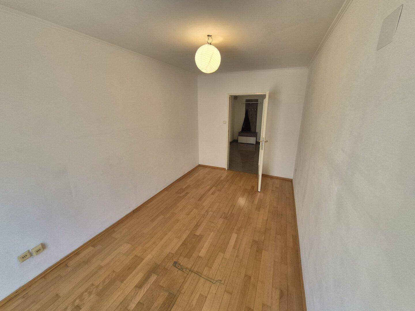 Schlafzimmer mit Parkettboden und weiß gestrichenen Wänden, bereit zur individuellen Gestaltung.