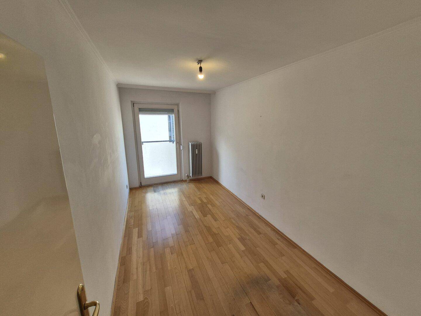 Geräumiges Schlafzimmer mit Parkettboden und Fenster, das für eine helle Atmosphäre sorgt.