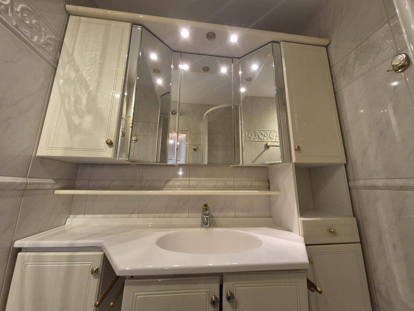 Waschtisch mit integriertem Waschbecken und großem Spiegelschrank im Badezimmer.