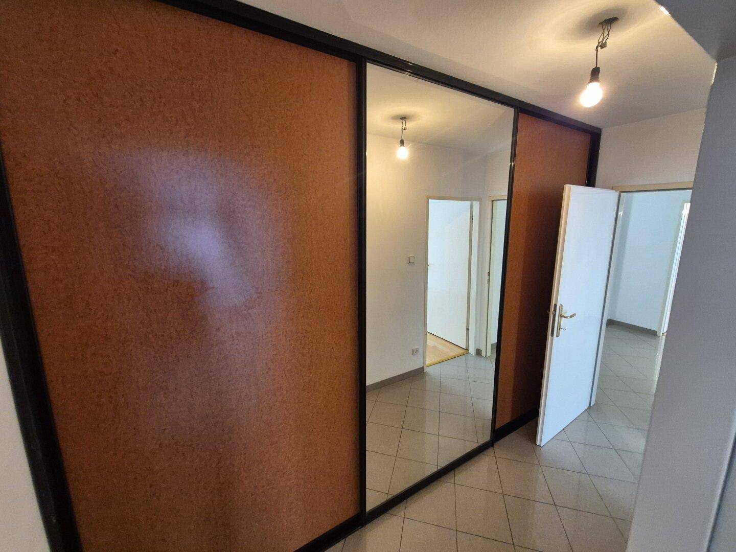 Flur mit großem Spiegelschrank und Fliesenboden, der zu weiteren Räumen führt.