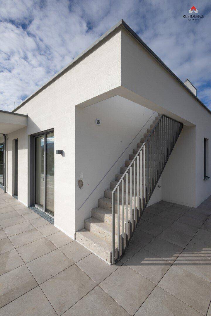 Moderne Gebäudefassade mit einer Außentreppe, die zu einer weiteren Ebene der Dachterrasse führt.