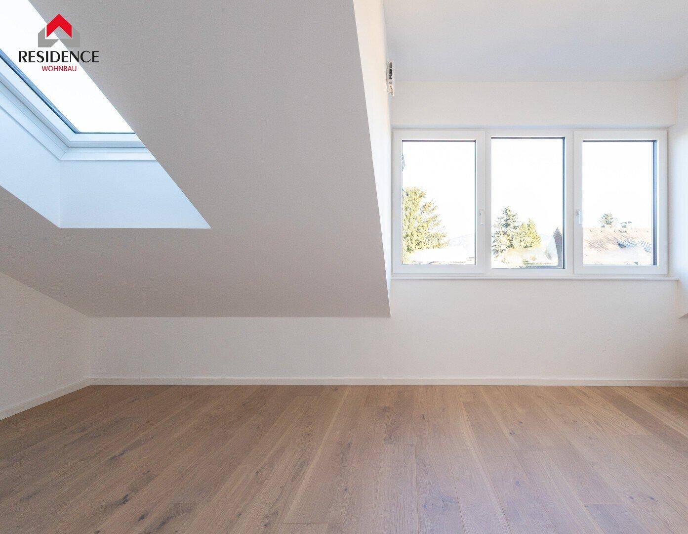 Heller Raum im Dachgeschoss mit Holzboden und großem Fenster.