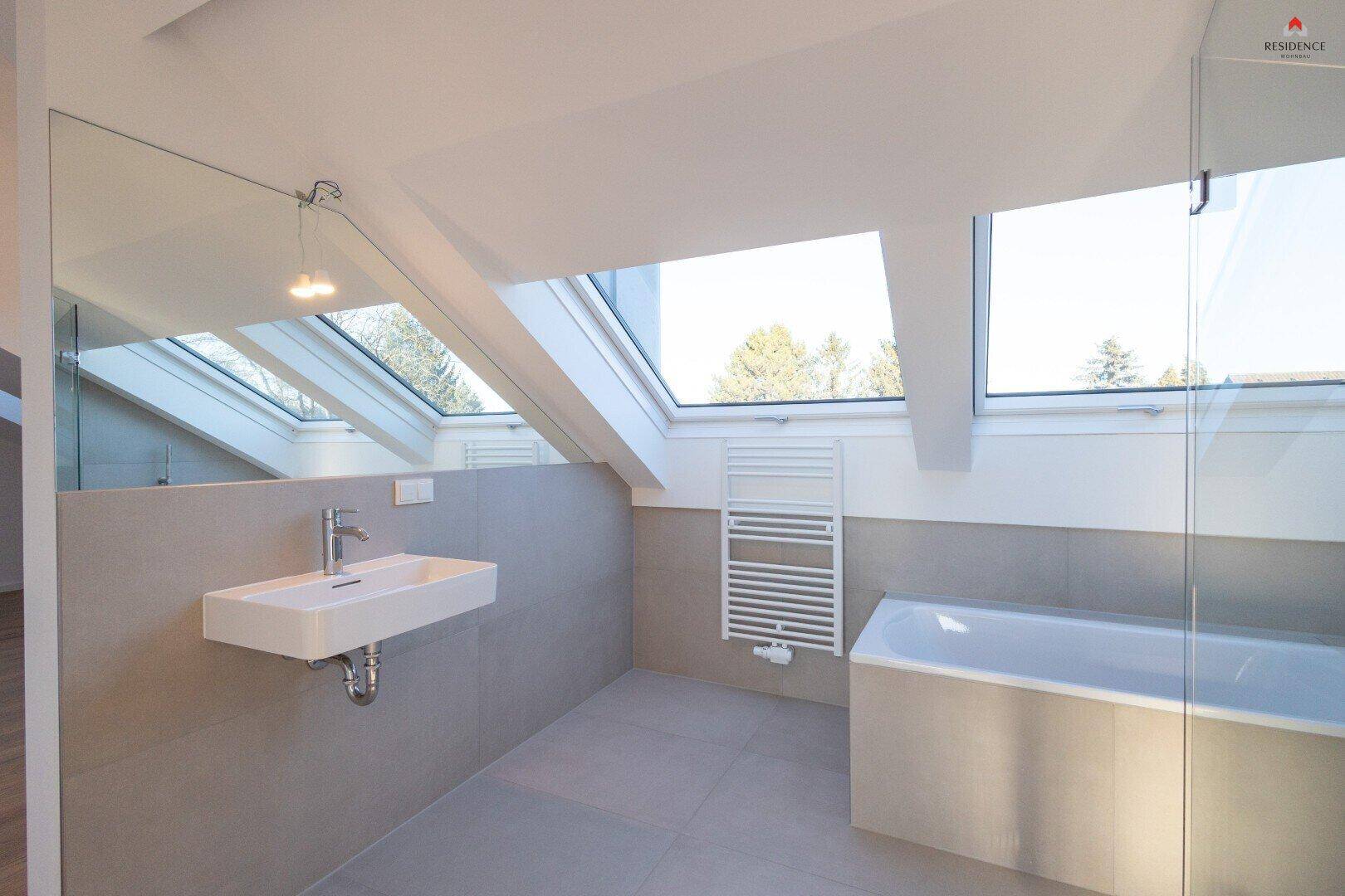 Modernes Badezimmer mit Badewanne, Dusche, schwebendem Waschbecken und Dachfenstern.