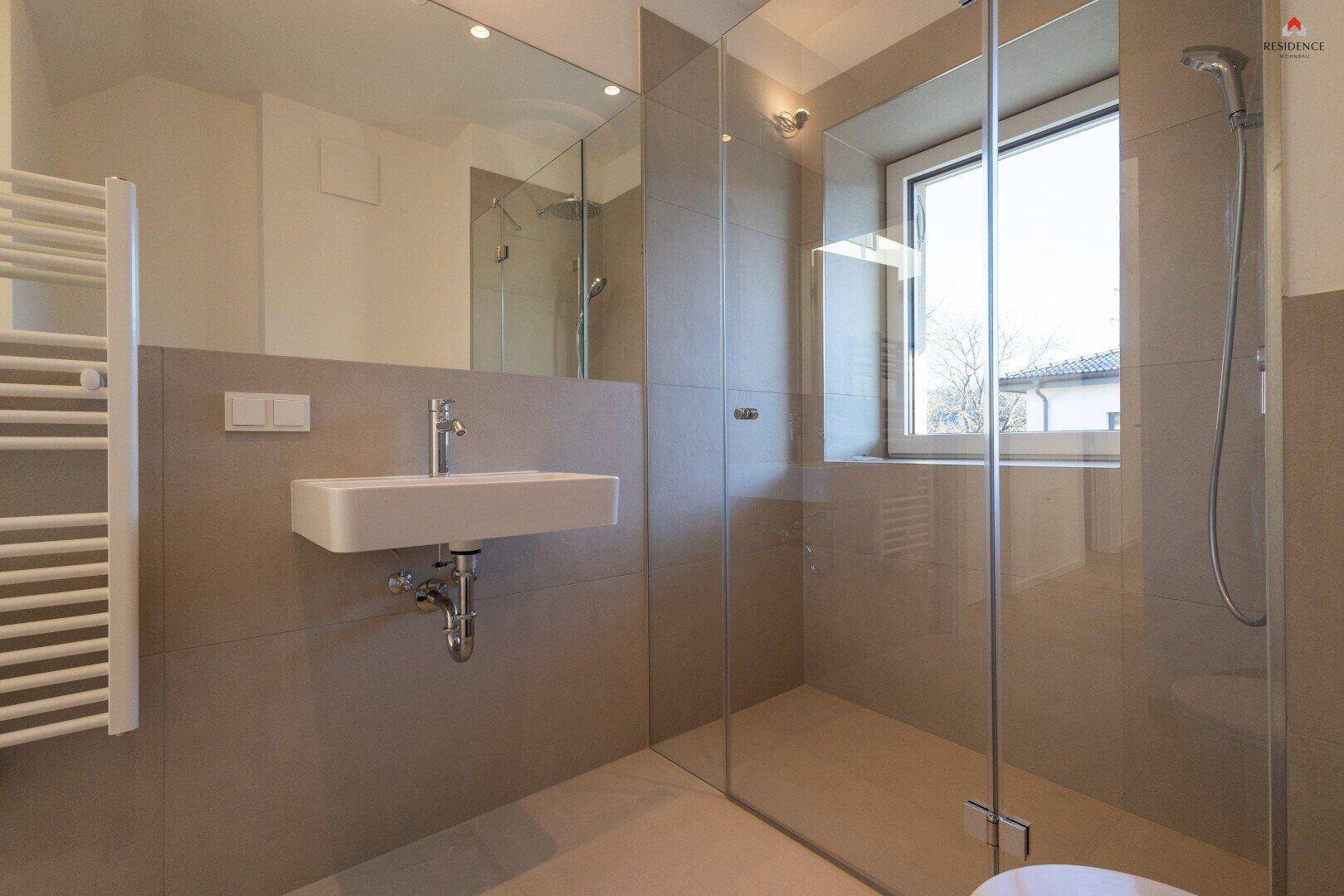 Modernes Badezimmer mit ebenerdiger Dusche, schwebendem Waschbecken, Handtuchheizkörper und Fenster.