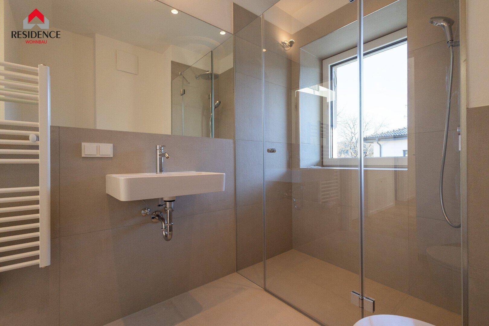 Modernes Badezimmer mit Fenster, Waschtisch, Dusche und Handtuchheizkörper.