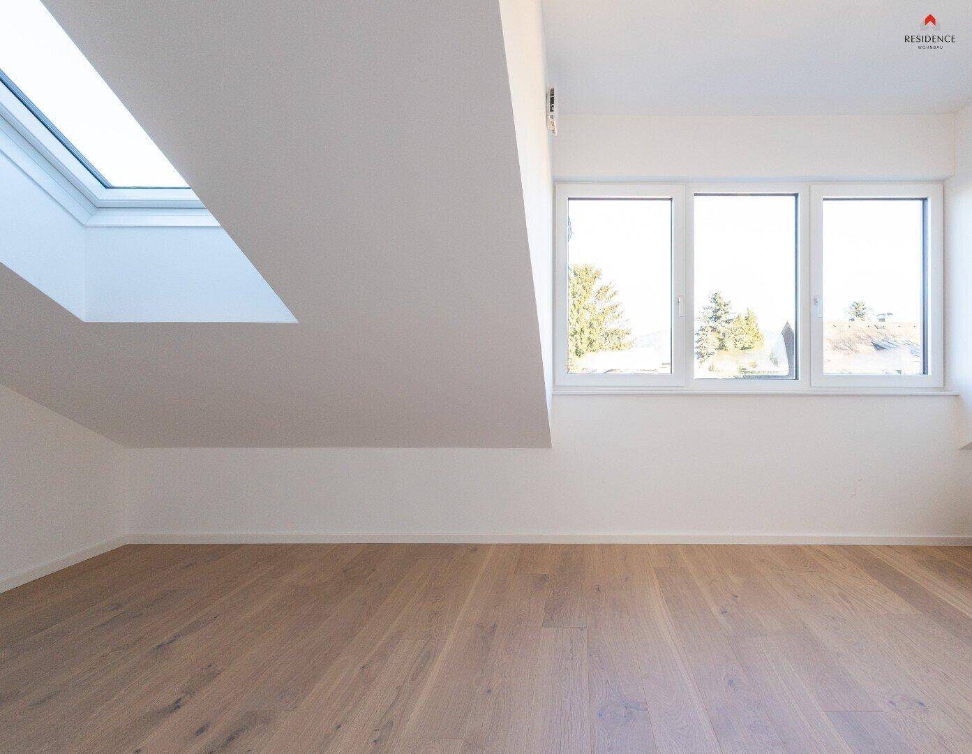 Helles Schlafzimmer mit Parkettboden, Dachschräge und Fenstern mit Ausblick sowie einem Dachfenster.