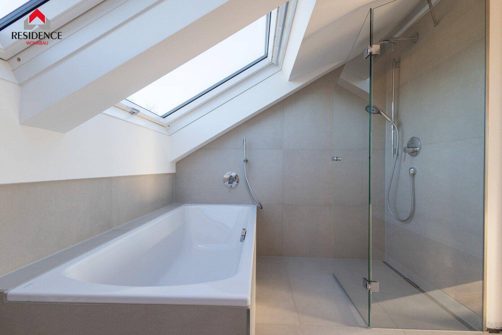 Helles Badezimmer mit Badewanne, Glasdusche und Dachfenster.