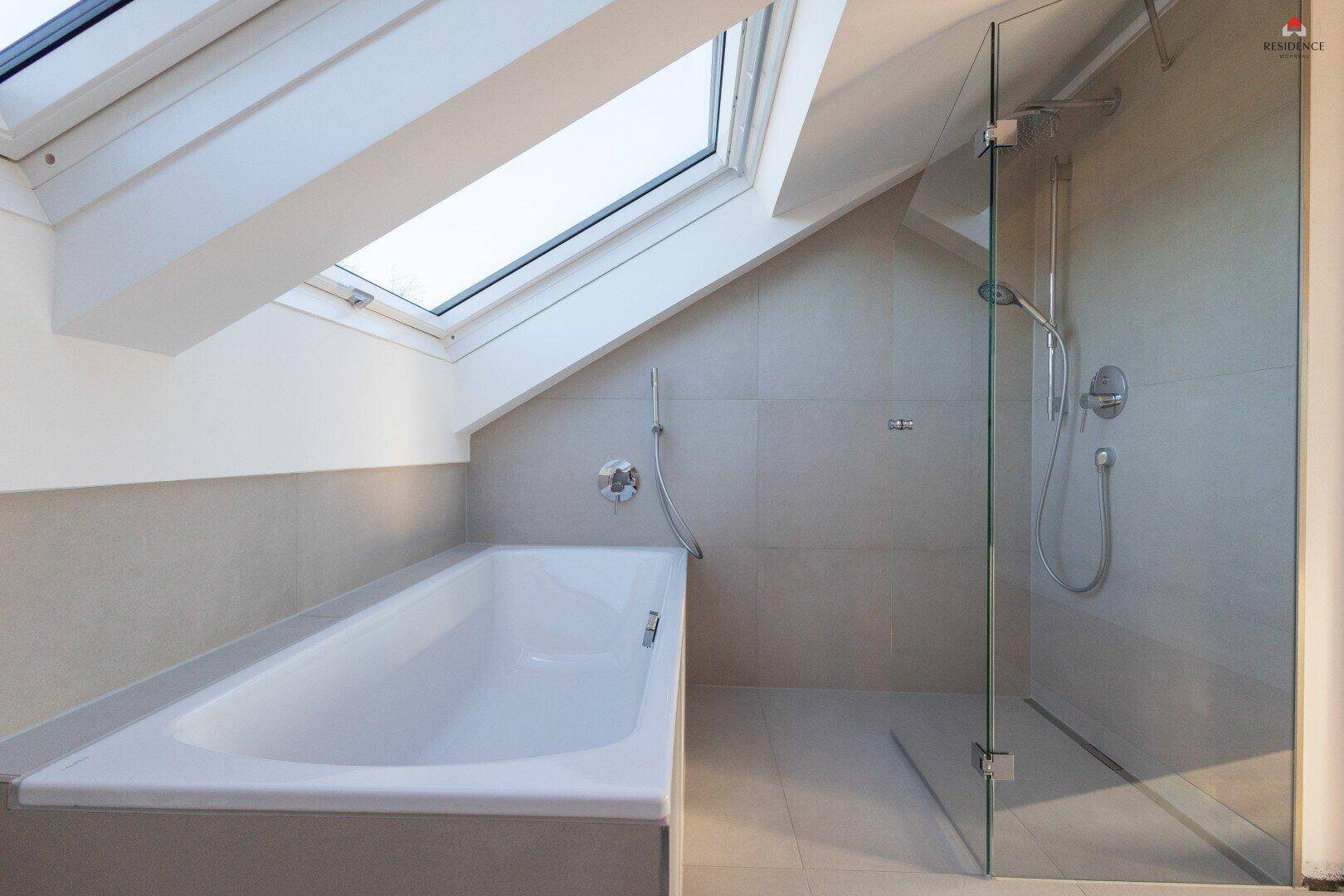 Helles Badezimmer mit Badewanne, ebenerdiger Dusche und einem großen Dachfenster für viel Licht.