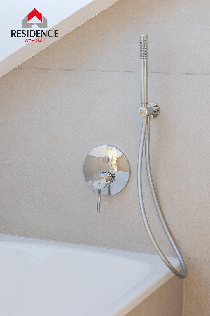 Nahaufnahme der modernen Duscharmatur über der Badewanne.