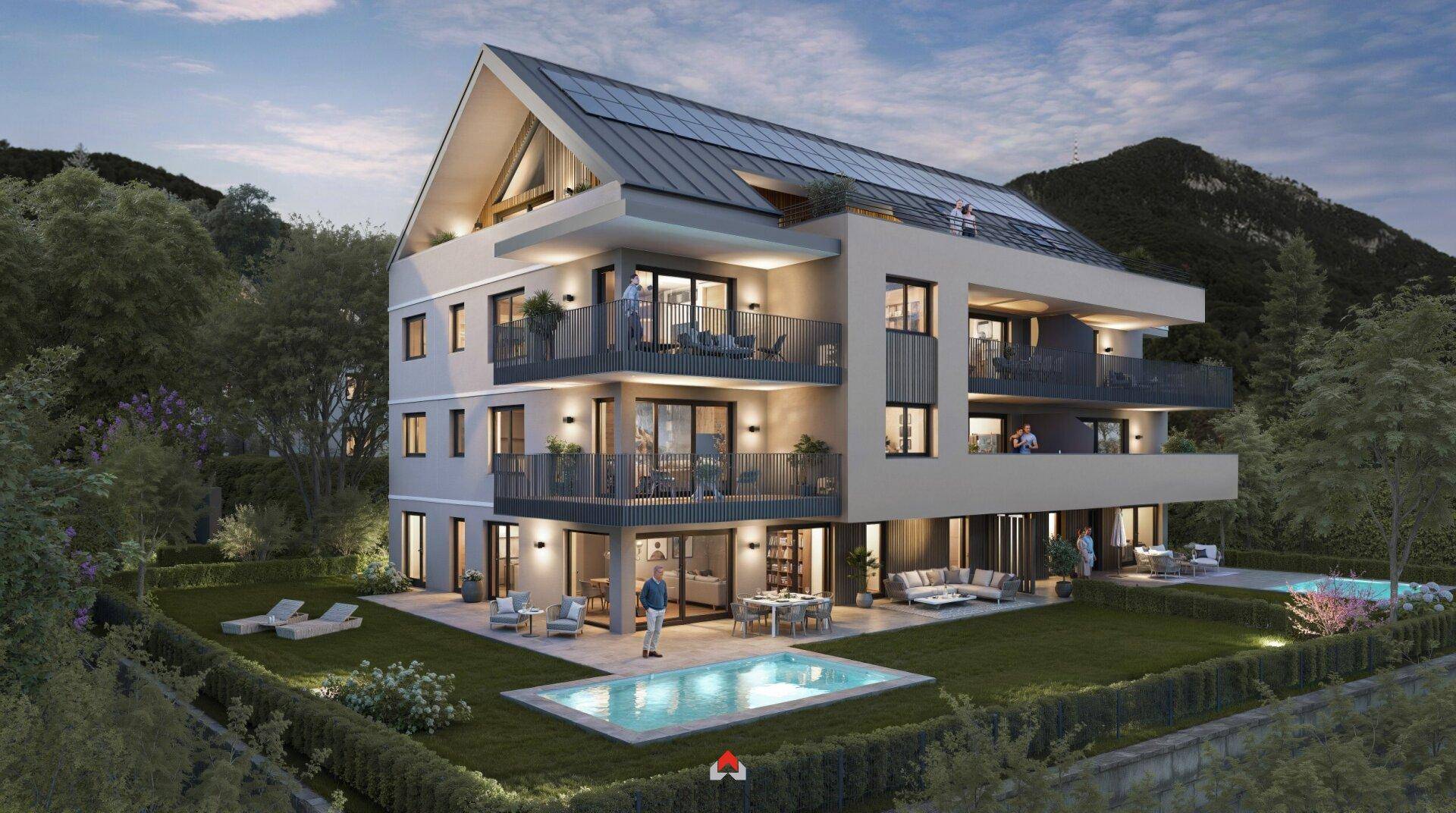 Abendliche Ansicht der modernen Wohnanlage mit Solaranlage, Balkonen, Terrassen und Bergblick.