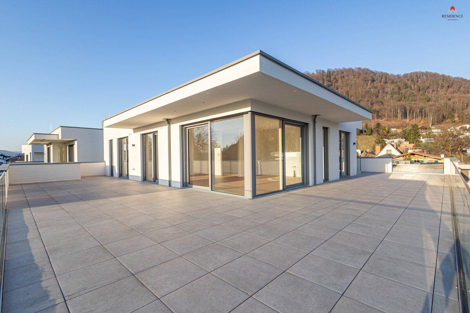 Geräumige, unmöblierte Dachterrasse mit Fliesenboden und Panoramablick auf die umliegende Berglandschaft.