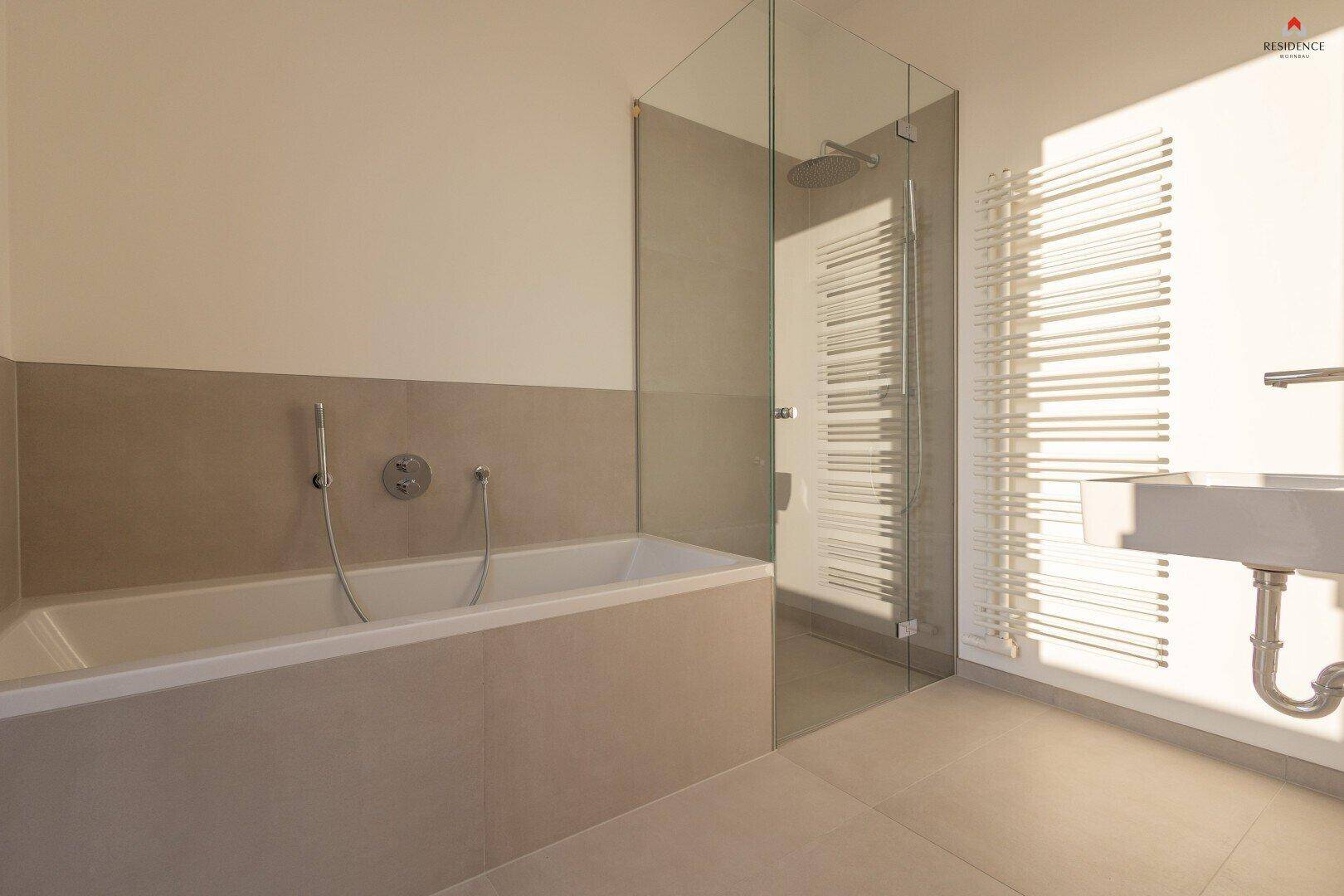 Modernes Badezimmer mit Badewanne, begehbarer Dusche und beheiztem Handtuchhalter in hellen Farbtönen.