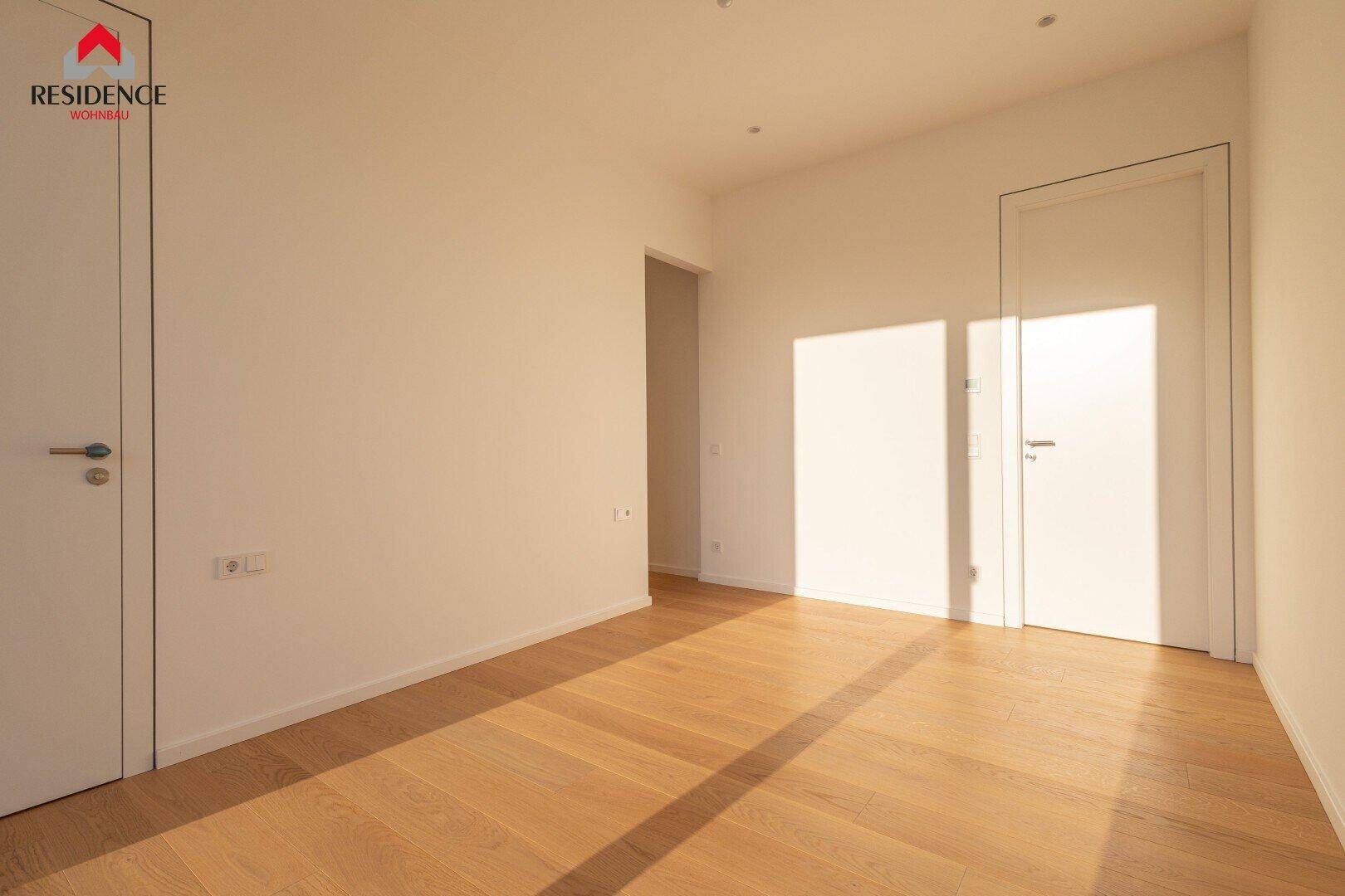 Helles Zimmer mit Holzboden und weiß gestrichenen Wänden, bereit zur individuellen Gestaltung.