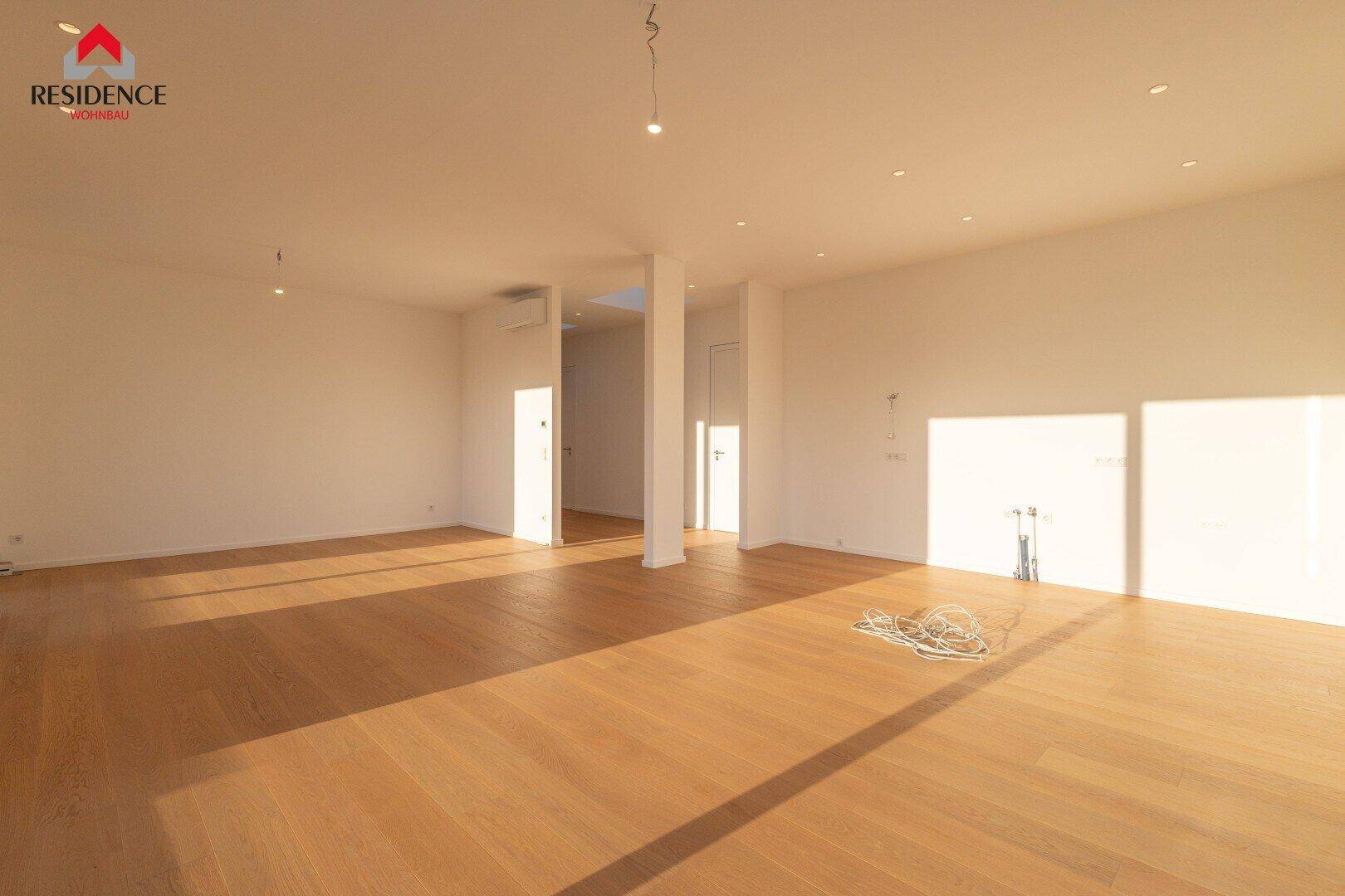 Geräumiger, heller Innenraum mit Holzboden und viel natürlichem Licht durch die Fenster.