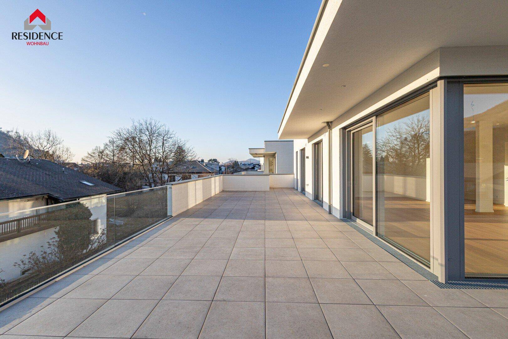Weitläufige Terrasse entlang der modernen Fassade mit viel Platz für Outdoor-Aktivitäten.