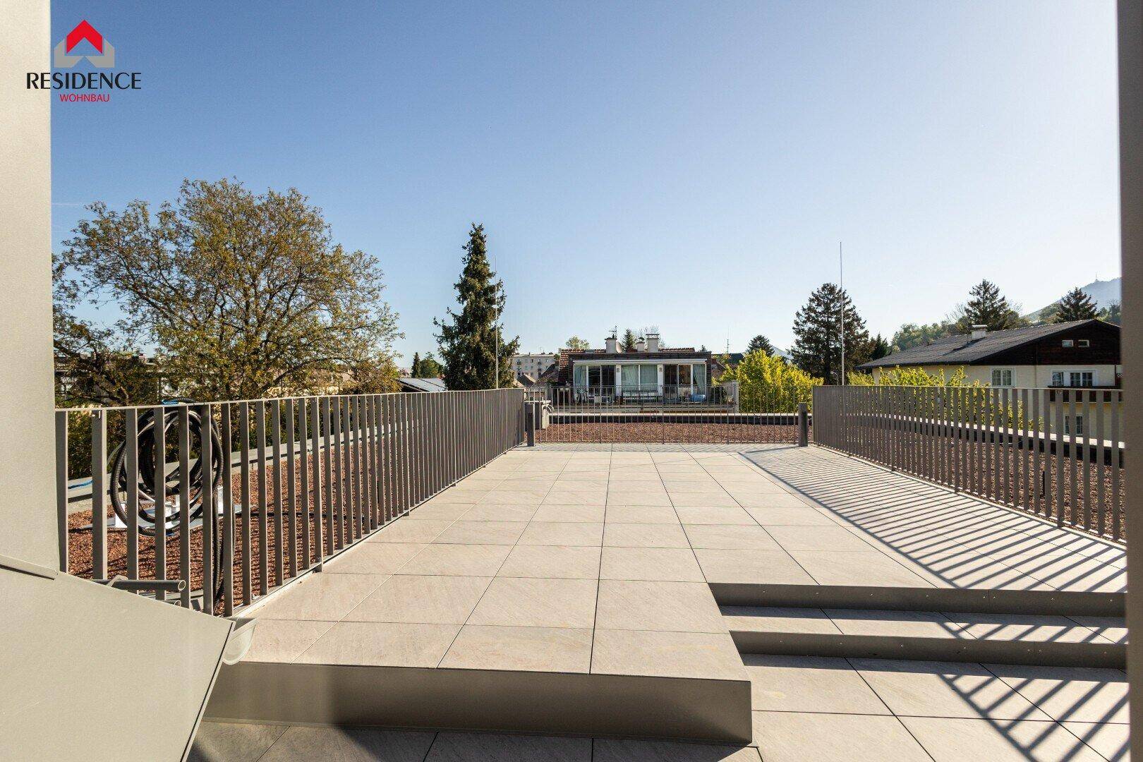 Große, unmöblierte Dachterrasse mit Fliesenboden und weitem Blick auf die Umgebung.