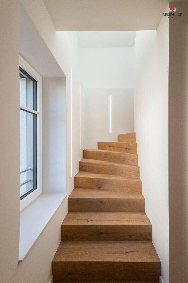 Elegante Holztreppe mit natürlichem Lichteinfall durch ein Fenster, verbindet die Etagen.