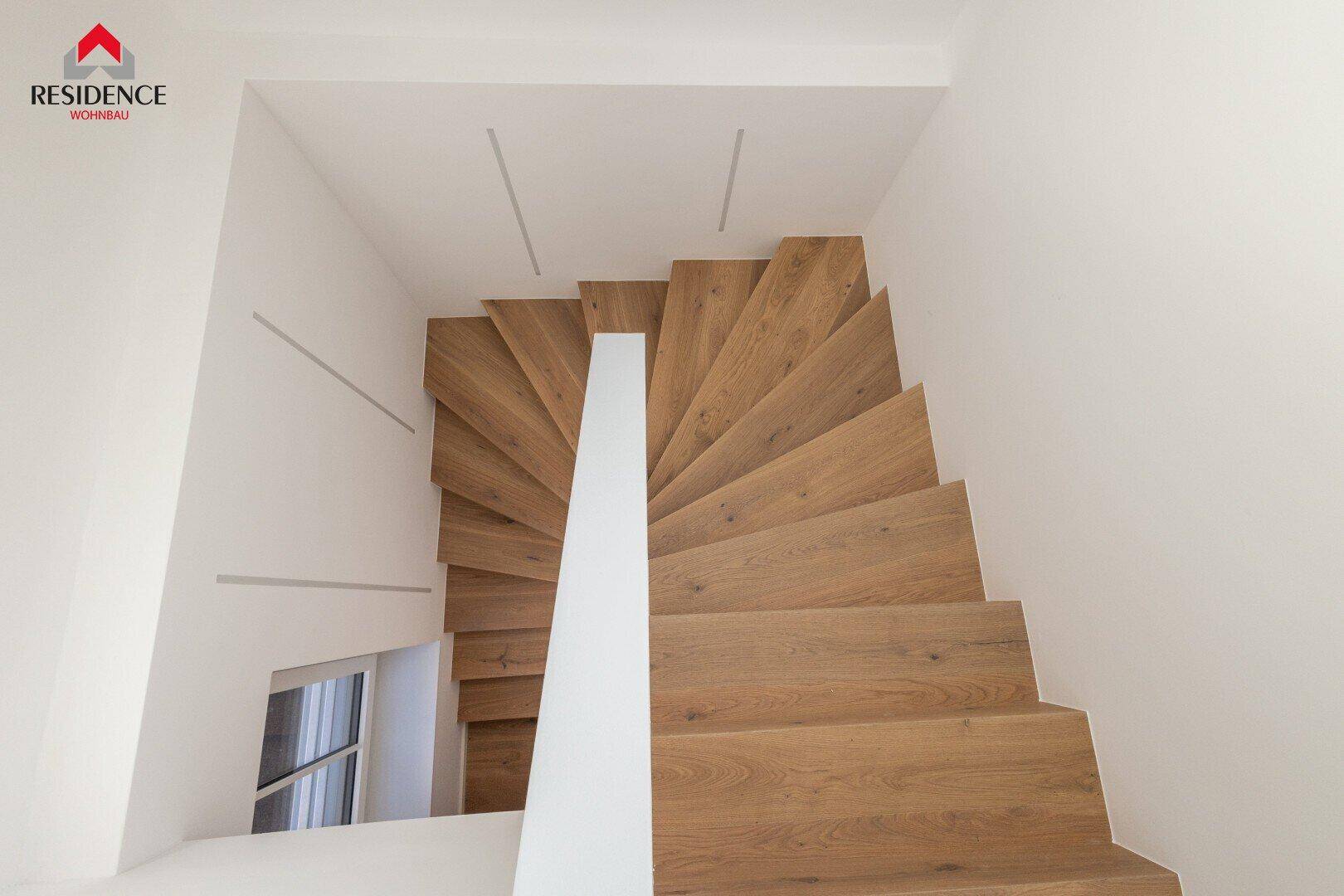 Moderne Holztreppe von oben gesehen mit integrierter Wandbeleuchtung und weißem Geländer.