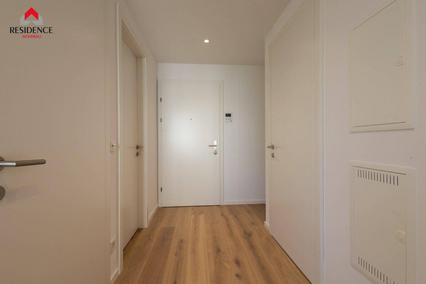 Heller Flur mit Holzboden und mehreren weißen Türen, die zu verschiedenen Räumen führen.