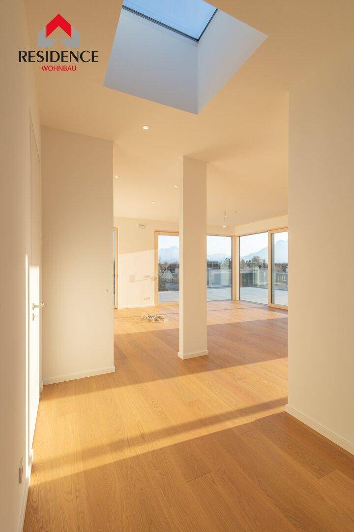 Heller, offener Wohnbereich mit Holzboden, großen Fenstern und Oberlicht für viel Tageslicht.