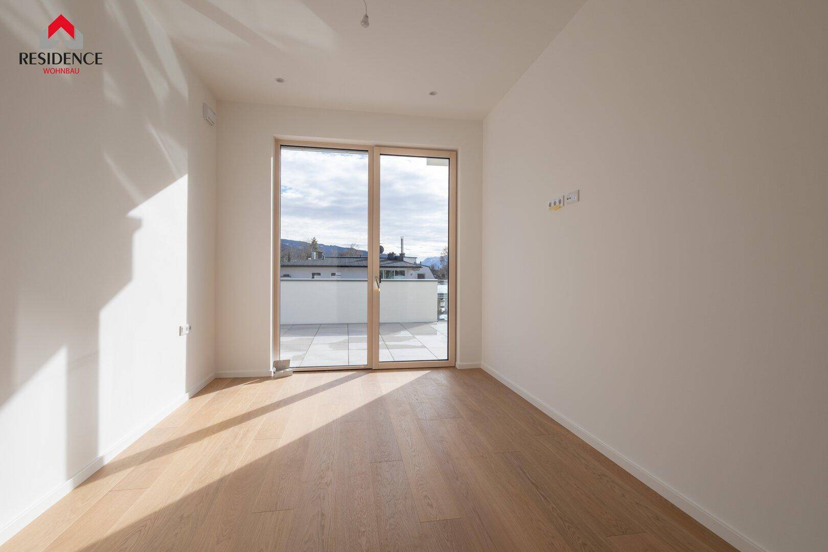 Helles Schlafzimmer mit Holzboden und Zugang zu einem Außenbereich mit Weitblick.
