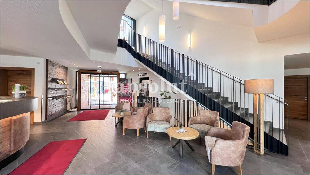 Einladende Lobby mit Sitzgelegenheiten, großzügigem Treppenhaus und modernem Design.