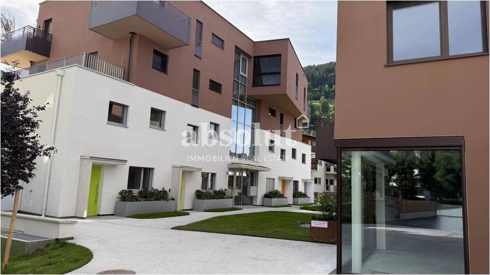 Ansicht einer modernen Wohnanlage mit unterschiedlichen Fassadenfarben und gepflegten Außenbereichen.