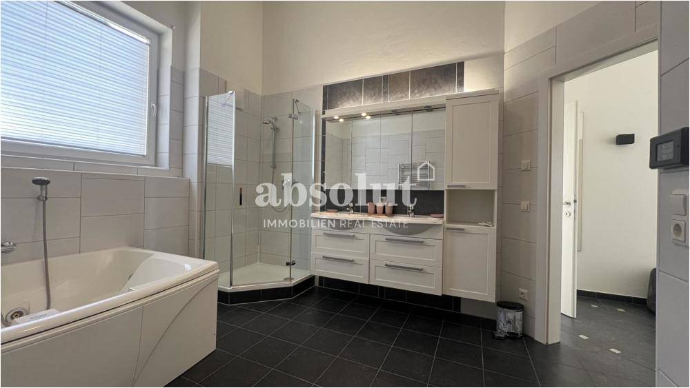Geräumiges Badezimmer mit Badewanne, Duschkabine und großem Waschtisch mit Spiegelschrank.