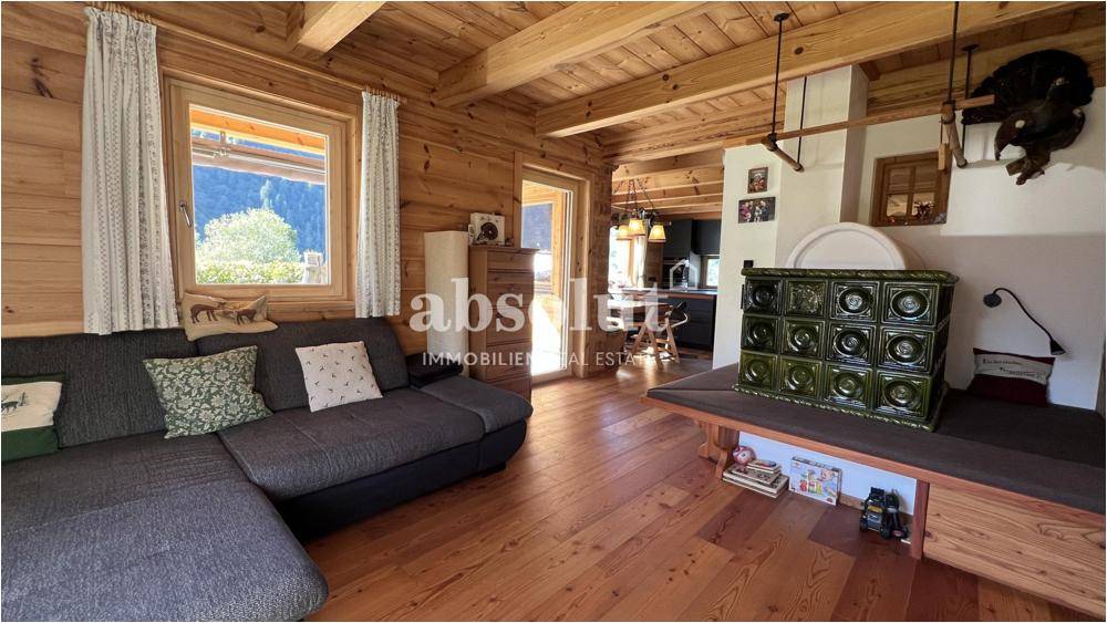 Rustikales Wohnzimmer mit Holzbalken, gemütlichem Sofa und traditionellem Kachelofen.