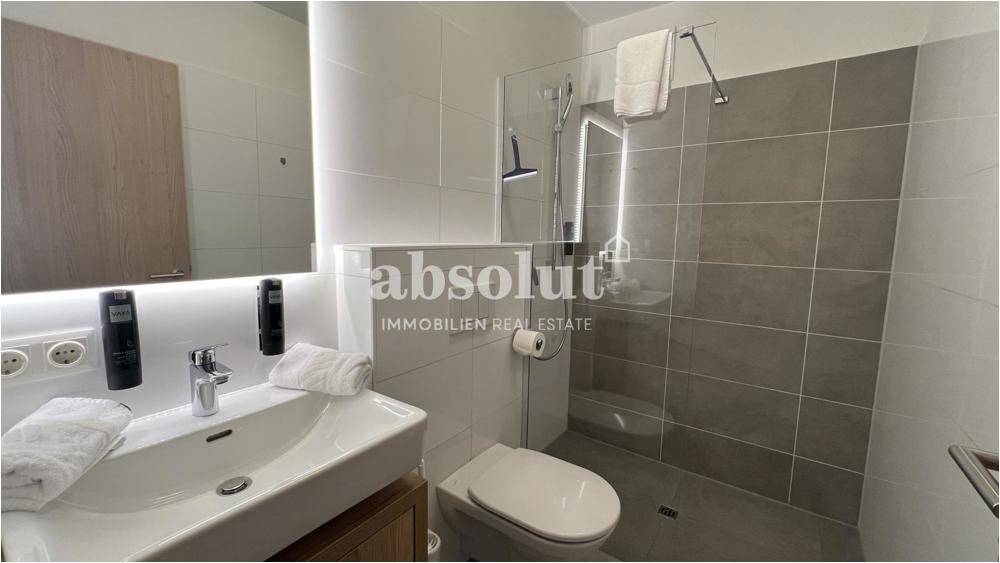 Modernes Badezimmer mit begehbarer Dusche, Wand-WC und Einzelwaschbecken.